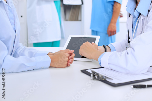 Doctor and patient are discussing something. Physician pointing into tablet computer