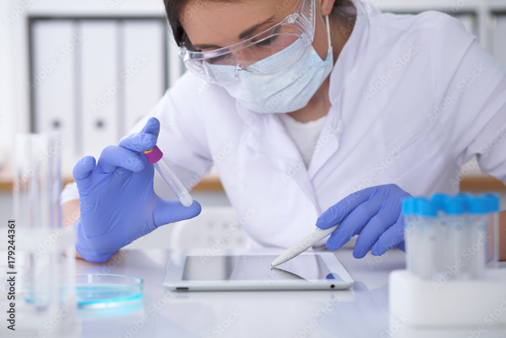 Close-up of professional female scientist in protective eyeglasses making experiment with reagents in laboratory. Medicine and research concept Close-up of professional female scientist in protective eyeglasses making experiment with reagents in laboratory. Medicine and research concept