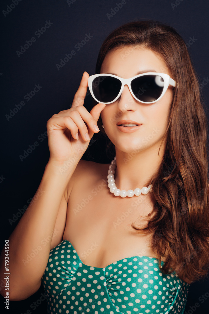 Woman on a dark background close-up in a swimsuit and wearing glasses. Pin-up style