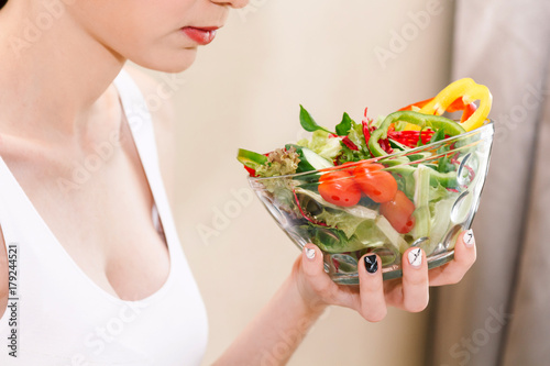 Woman holding fresh vegetable salad in glass bowl. Woman diet concept