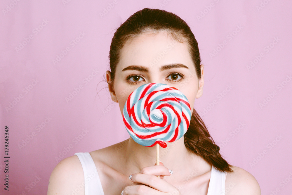 Woman holding a lollipop on pink background