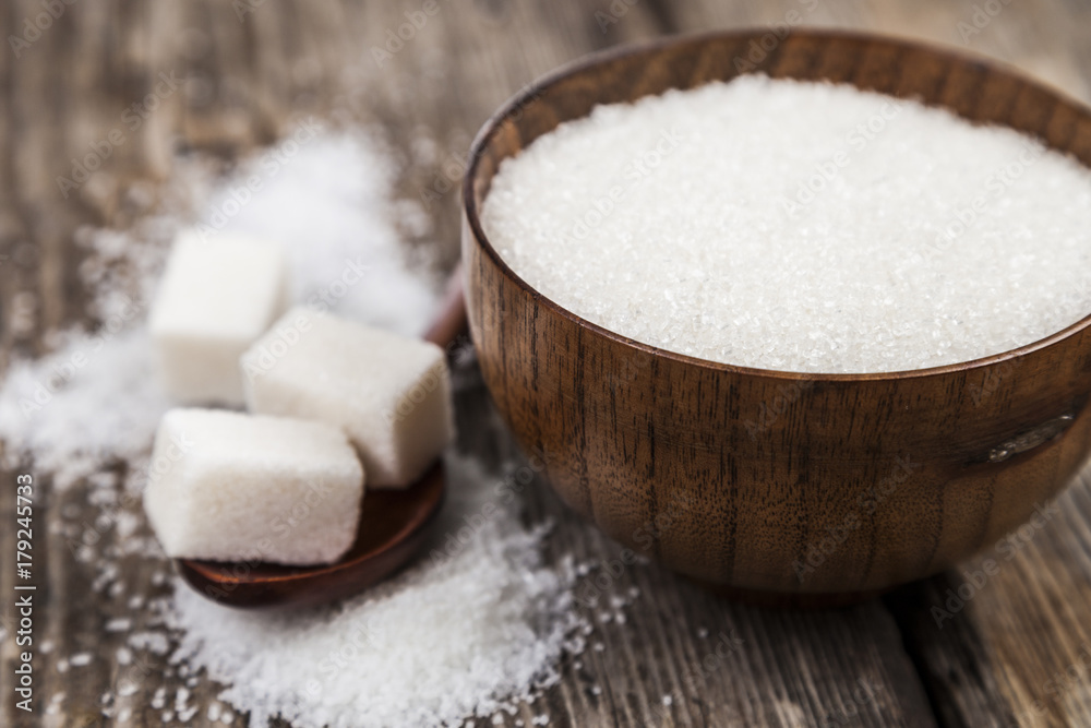 Sugar in a wooden bowl and a spoon