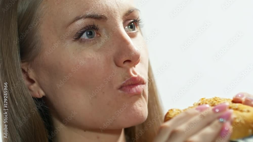 Tilt up with of businesswoman eating cheeseburger with fresh lettuce and dollar bills Tilt up with of businesswoman eating cheeseburger with fresh lettuce and dollar bills