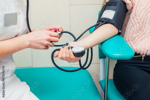 Close up view of female medicine doctor measuring blood pressure to her patient. Hands close up. Healthcare  healthy lifestyle and medical service concept. Space for text