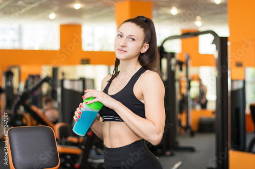 Sporty girl with a protein drink in the gym