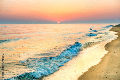 Sunset on the beach with long coastline, sun and dramatic sky 