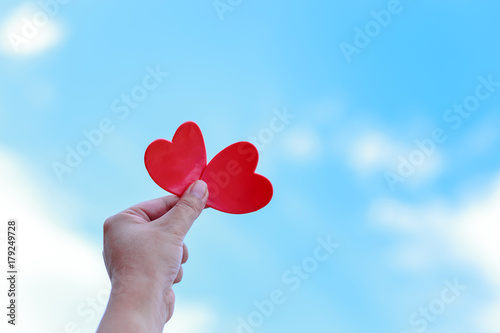 Heart in the hand on blue sky background