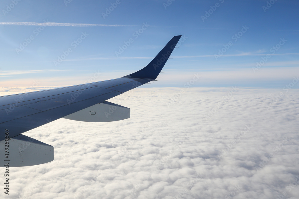 Wing of airplane flying above the clouds