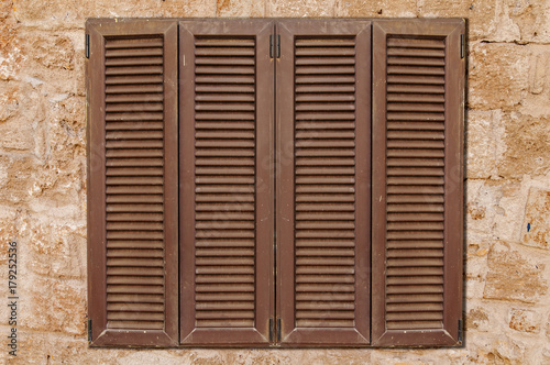 Brown wooden window on yellow castle old stone pattern texture wall close