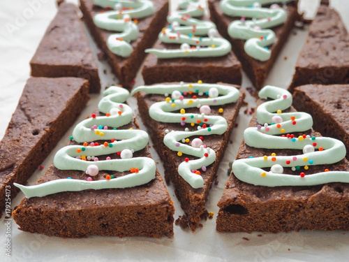Triangle brownie dessert. Preparing Christmas treat. Decorating chocolate cake as Christmas tree. 