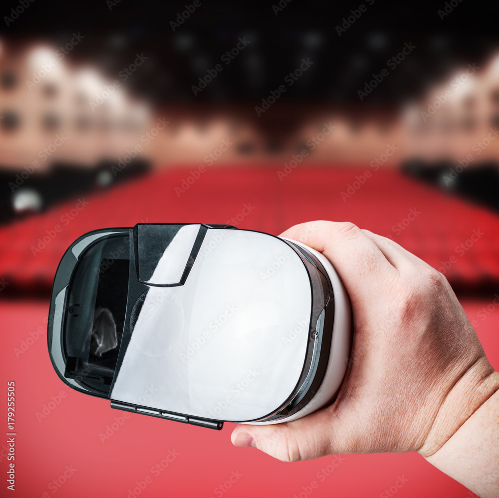 Obraz premium hand holds virtual reality glasses on the background of cinema