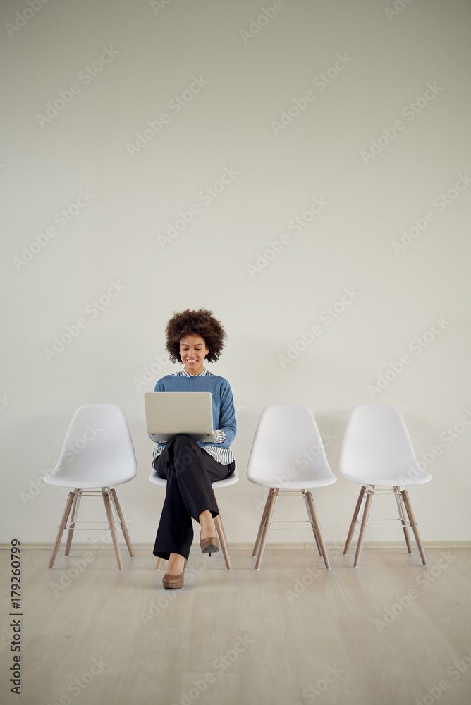 Fototapeta premium African American businesswoman sitting in waiting room and using laptop