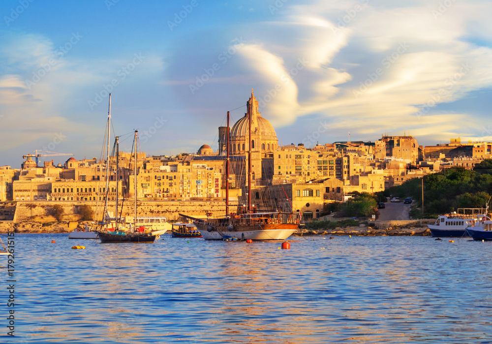 Beautiful travel scene with a red motor boat on the harbor in Valletta Capital, Malta