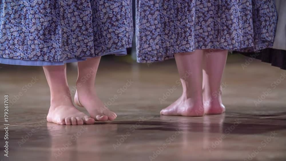 Young girls are barefoot and are singing and dancing on stage. They're wearing long dresses which are a national costume. Young girls are barefoot and are singing and dancing on stage. They're wearing long dresses which are a national costume.