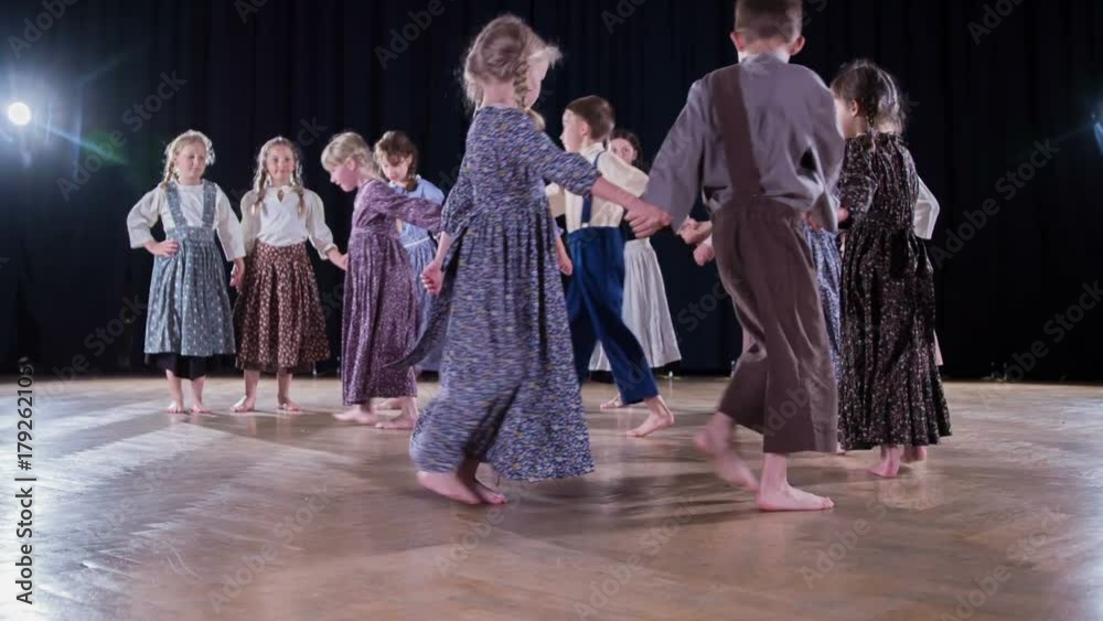 Pupils in the elementary school are wearing national costumes and they are dancing and performing in a school play.