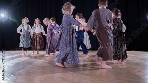 Pupils in the elementary school are wearing national costumes and they are dancing and performing in a school play.