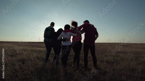 Group of five people warming against wind farm at sunset movement stabilized shot