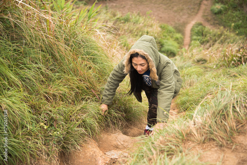 Female tourist climbing high hill to tropical mountain view point