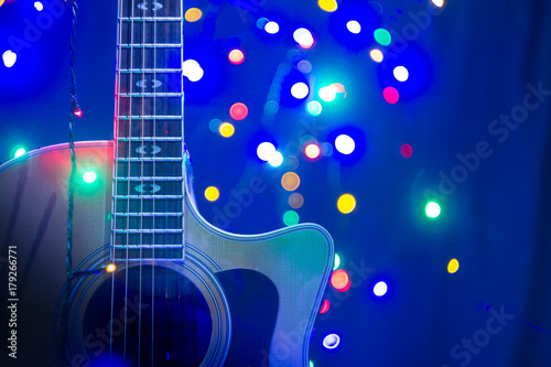 A part of yellow acoustic guitar with New Year or Christmass garlands on a blue background. Celebrating atmosphere.