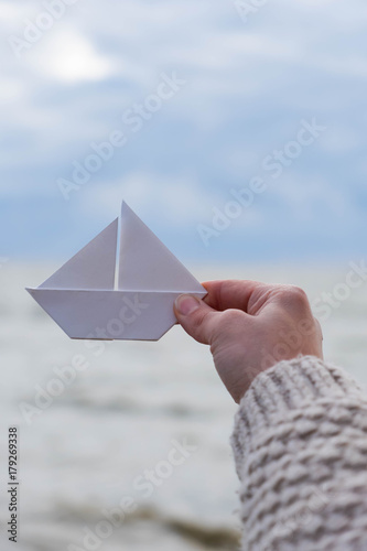 Close-up of human hand paper boat sea backround