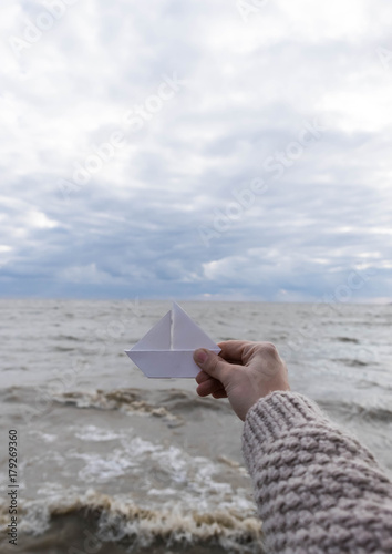 Close-up of human hand paper boat sea backround
