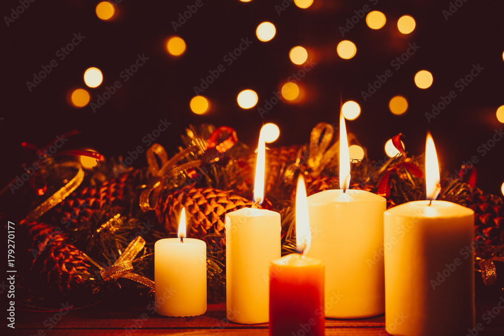 Φωτογραφία Christmas burning candles on wooden table on the bokeh background of luminous garlands at night