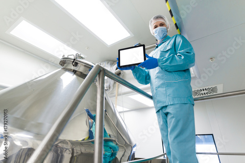 plant picture, scientist is showing empty tablet near barrel photo