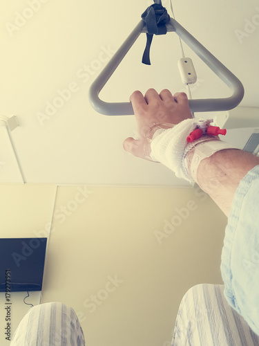 Patient holding a trapeze on a bed - point of view. photo