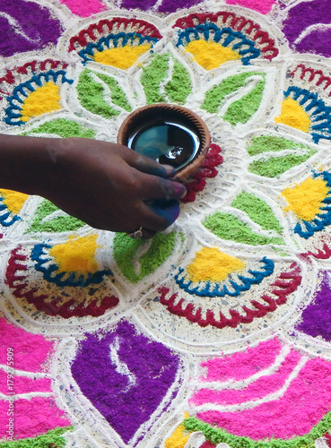 hand drawing Kolam,Rangoli, Alpana or Chowk pujan decorative patterns using colored powders on floor in front of door on festivals,celebrations,occasions as Indian Hindu tradition