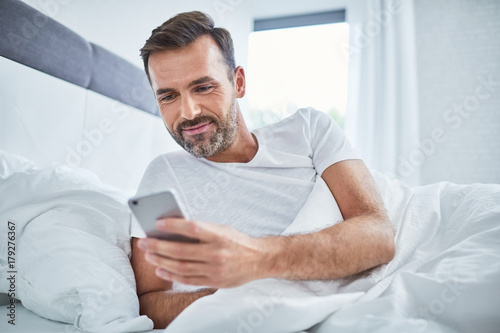 Photography Handsome man using phone in bed after waking up in the morning
