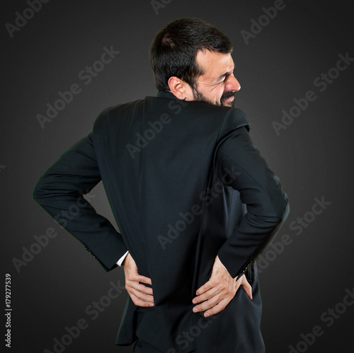 Handsome businessman with back pain on black background