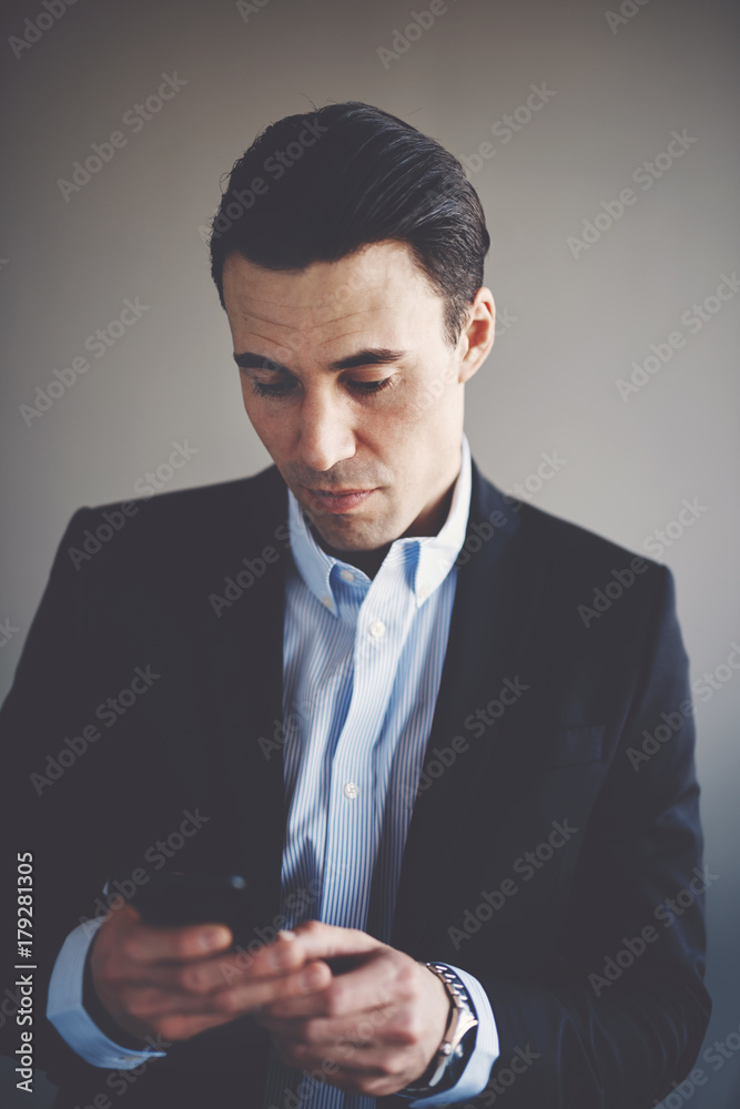 Focused young businessman reading text messages on a cellphone Focused young businessman reading text messages on a cellphone