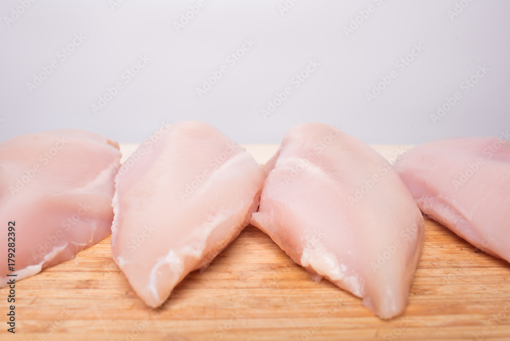 Fresh chicken fillet on a bamboo cutting board on a light background