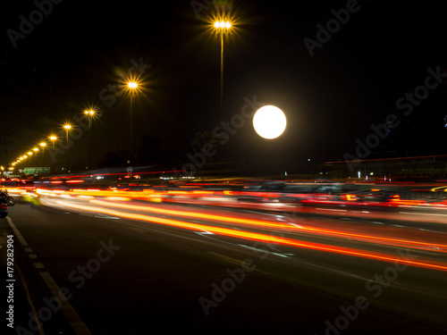 Motion light of traffic with big full moon at night