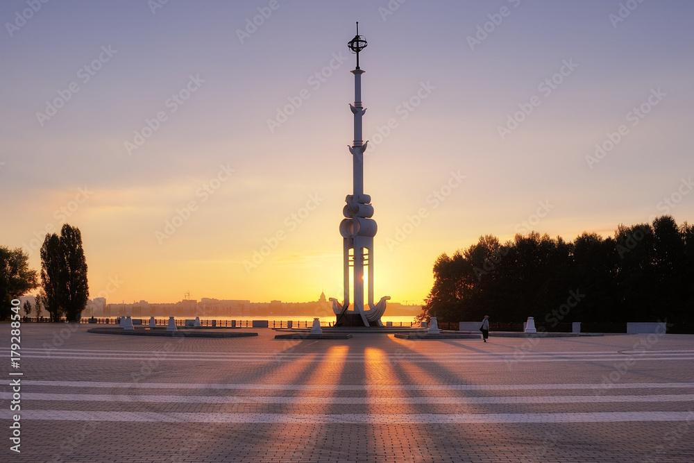 Sunrise at the Admiralty Square. The first solar rays penetrate the rostral column in the Admiralty Square in the summer. Warm summer light at dawn. A lonely man walks in the morning at dawn.