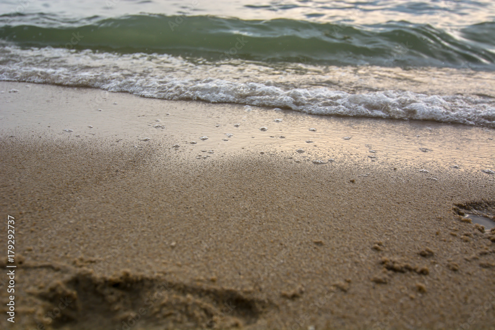 Artistic photo. Close-up on a wave withdrawing on the sand of a beach in the sunset Artistic photo. Close-up on a wave withdrawing on the sand of a beach in the sunset