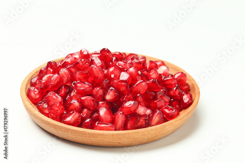 pomegranate seeds in wooden plate isolated on white background
