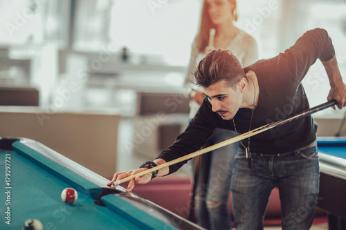Group of young friends playing billiard in cafe