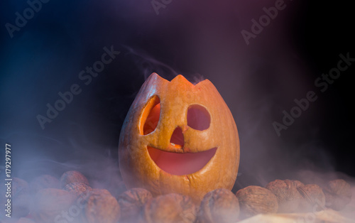 halloween pumpkin on nuts in colorful smoke 