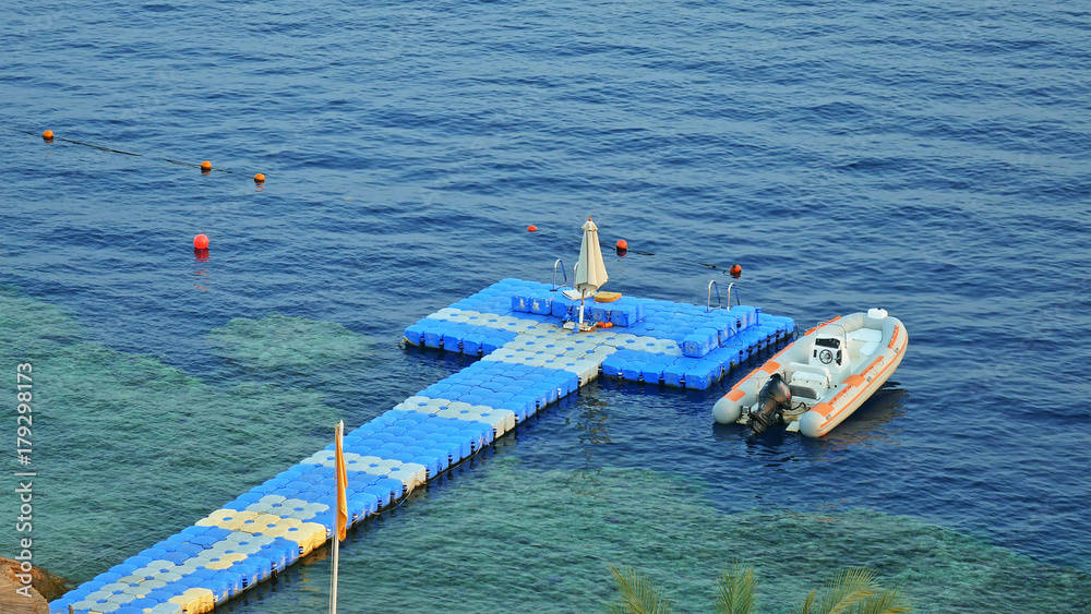Floating jetty dock over coral reef at the tropical sea resort. Powerboat is moored up to the