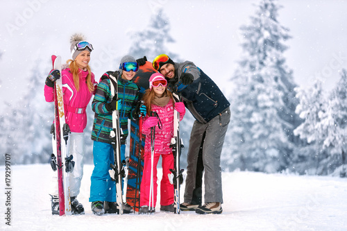 Family with ski equipment looking something together