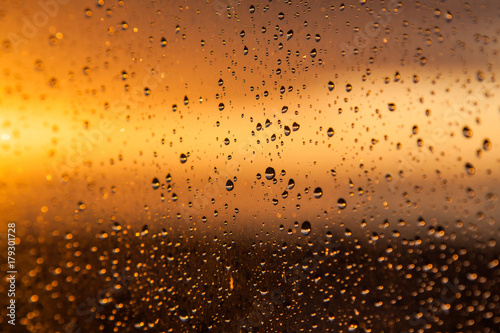 Rain drops on a window at sunset