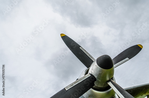Close up of airplane turboprop engine with propeller, parts of aircraft fuselage, wings and tail on a cloudy sky background