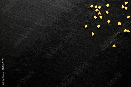 Few golden sugar stars on black background with space for your message