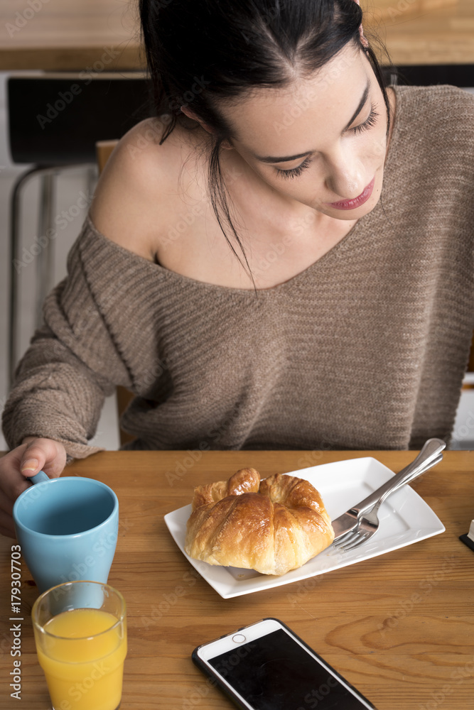 Beautiful woman drinking coffee and eating croissant Beautiful woman drinking coffee and eating croissant