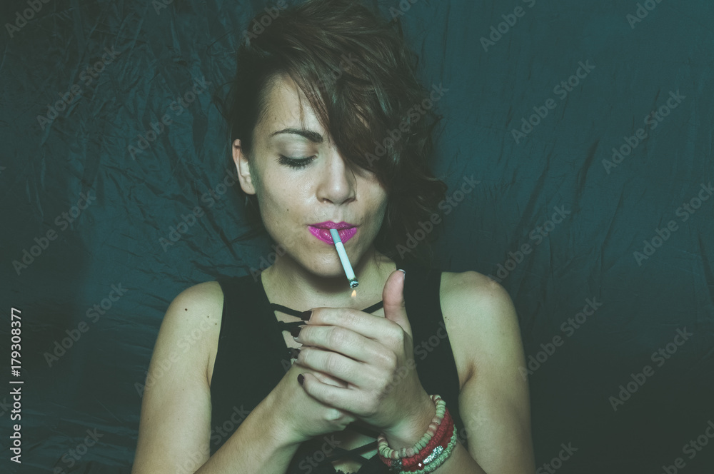 Obraz premium Abstract dark portrait of beautiful young girl with messy hair holding and lightning cigarette
