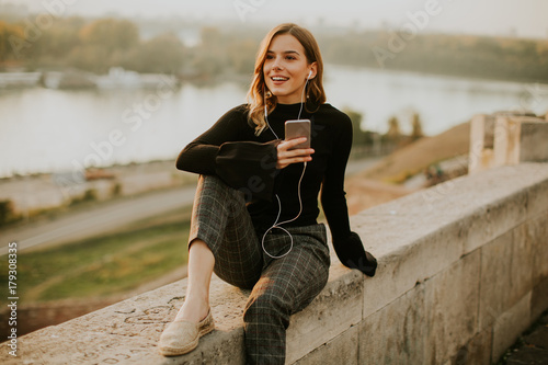 Trendy young woman listenin...