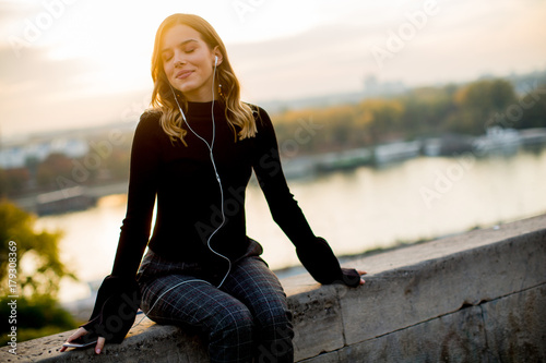 Trendy young woman listenin...