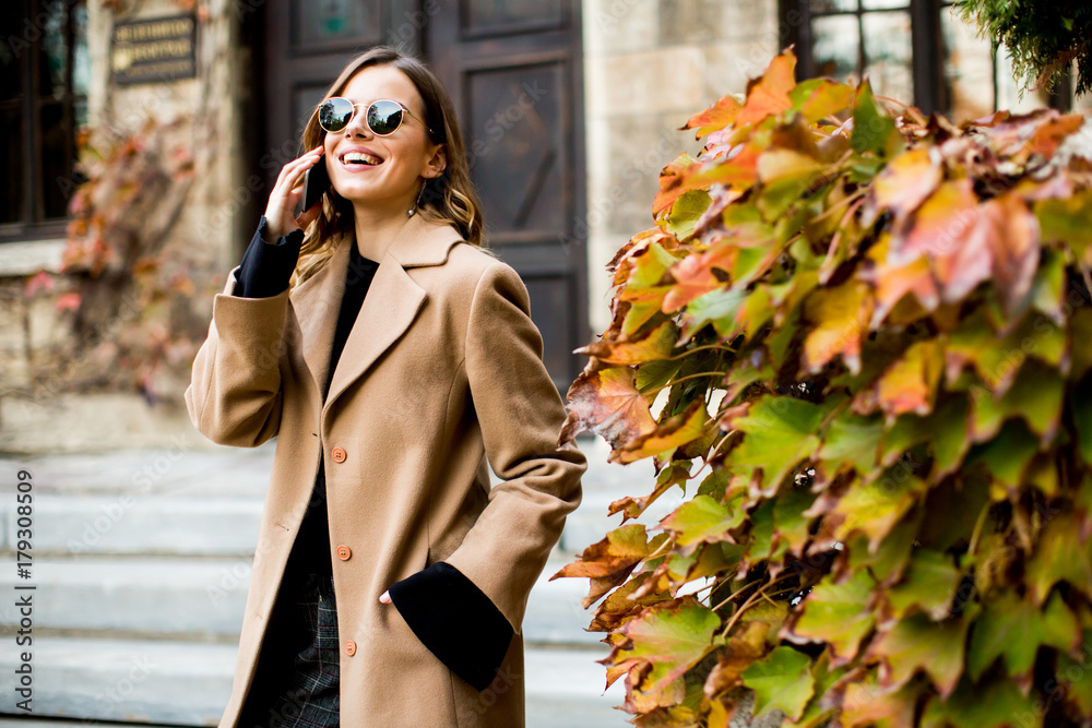 Fototapeta premium Modern woman using mobile phone at autumn outdoor