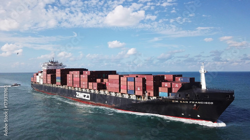 Huge large mega ULCV container ship sails on open water fully loaded with containers and cargo - aerial view
